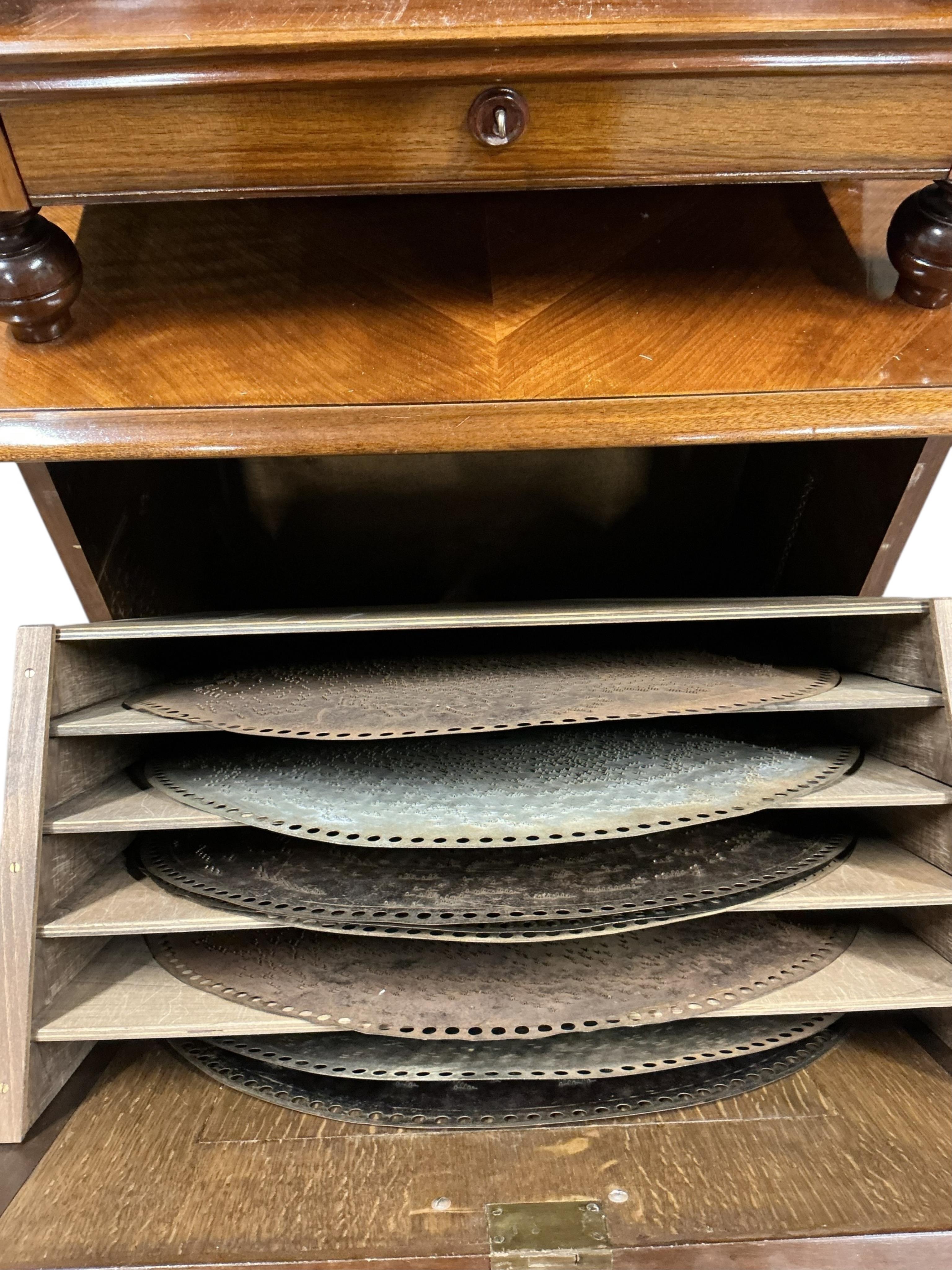 A floor standing coin-operated walnut polyphon disc player with nine 50cm diameter discs, the base containing storage compartments for the discs, coin slots on both sides with guilt finished surrounds next to applied lab